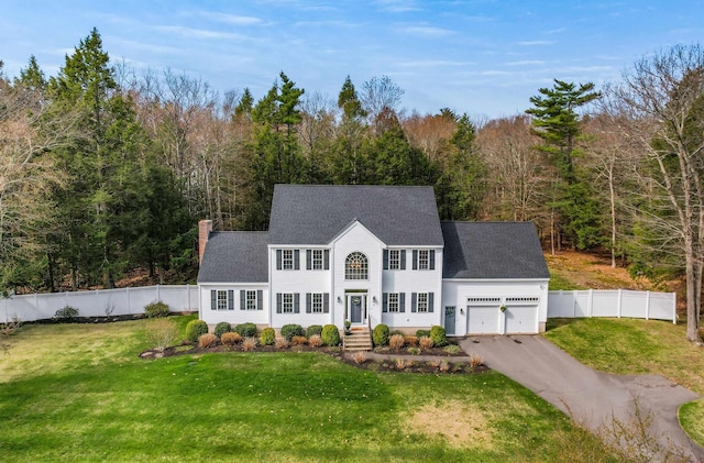 view of front of house with a front yard, a garage, fence, aphalt driveway, and a shingled roof