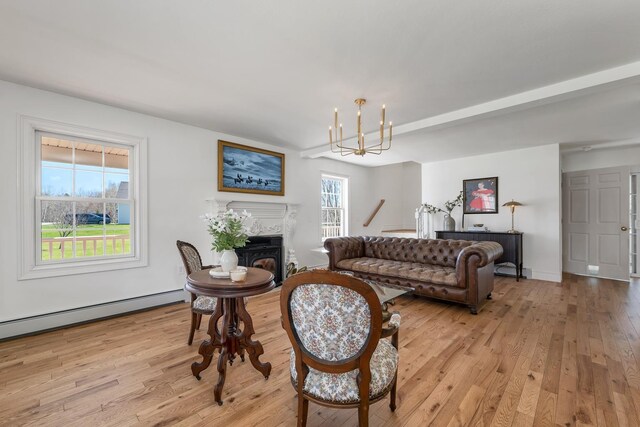 living room with baseboard heating, an inviting chandelier, and light wood-style flooring
