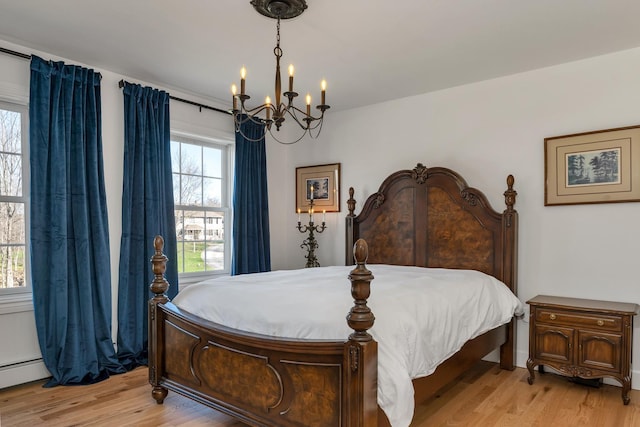 bedroom with a chandelier, baseboard heating, and light wood finished floors