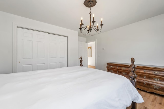 bedroom with a chandelier, wood finished floors, and a closet