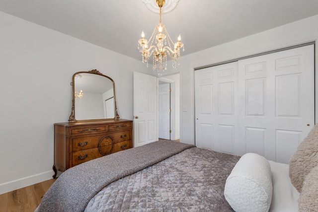 bedroom with baseboards, a chandelier, wood finished floors, and a closet