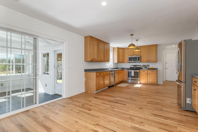 kitchen featuring light wood-style floors, baseboards, stainless steel appliances, and dark countertops