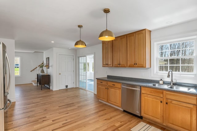 kitchen featuring a sink, dark countertops, stainless steel appliances, and a healthy amount of sunlight