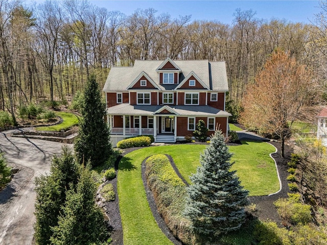 shingle-style home featuring a porch, driveway, and a front yard