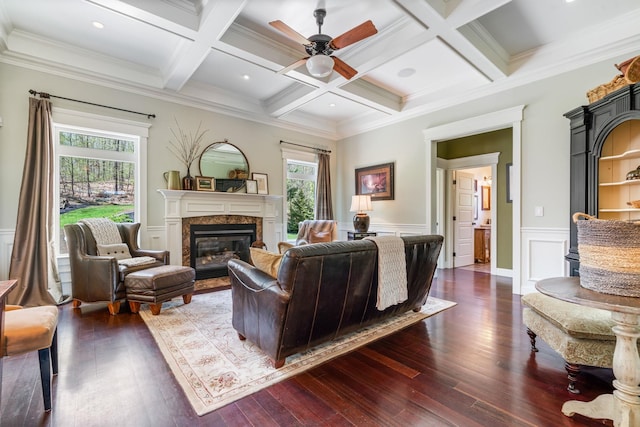 living area featuring a ceiling fan, dark wood-style floors, a premium fireplace, and beamed ceiling