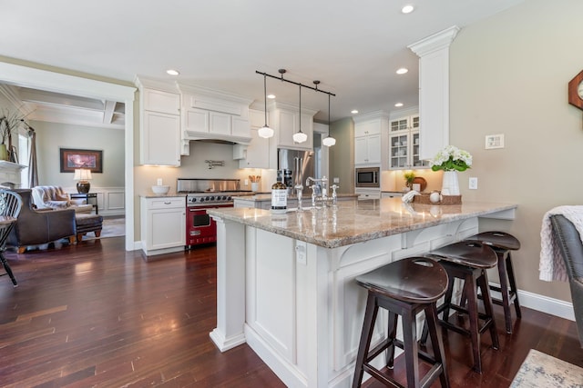 kitchen with a peninsula, a breakfast bar, glass insert cabinets, recessed lighting, and appliances with stainless steel finishes