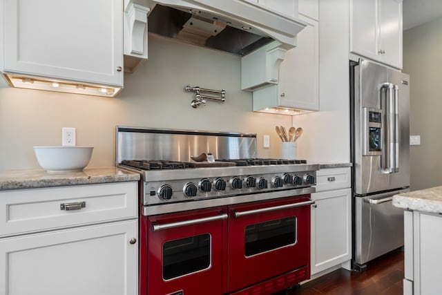 kitchen featuring white cabinets, light stone countertops, high end appliances, dark wood-type flooring, and custom exhaust hood
