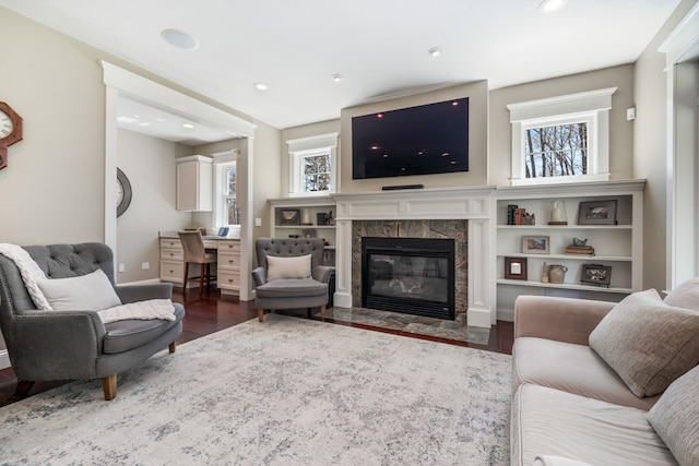 living area with dark wood-type flooring, recessed lighting, baseboards, and a high end fireplace
