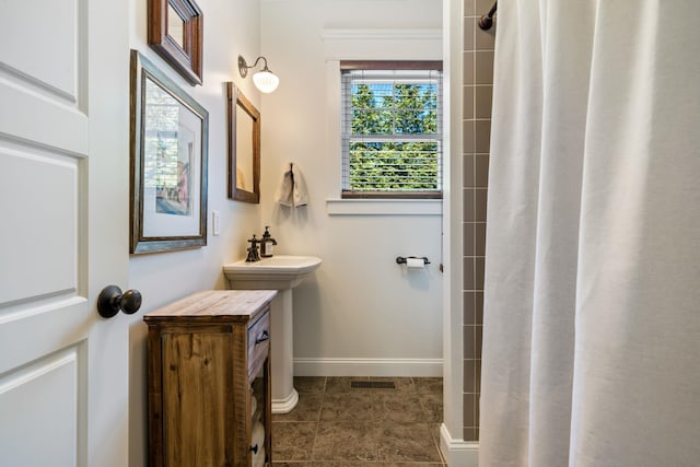 full bath featuring a tile shower, a sink, tile patterned flooring, baseboards, and visible vents