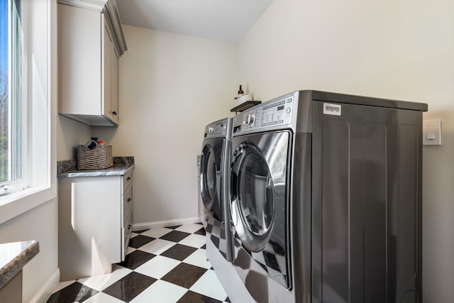 laundry room with separate washer and dryer, light floors, cabinet space, and baseboards