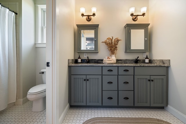 full bathroom featuring baseboards, double vanity, a sink, and toilet