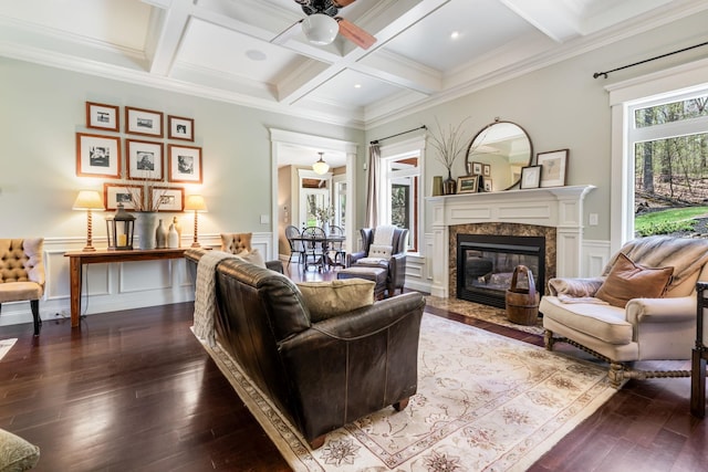 living area with dark wood-style flooring, beamed ceiling, ceiling fan, coffered ceiling, and a premium fireplace