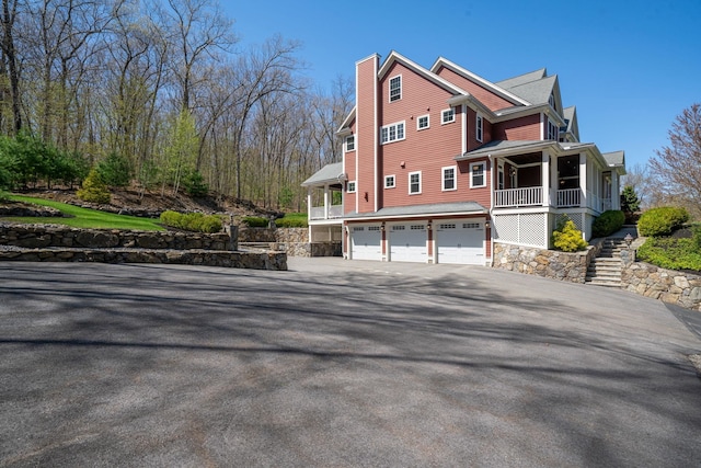 view of property exterior with a garage, aphalt driveway, and a chimney