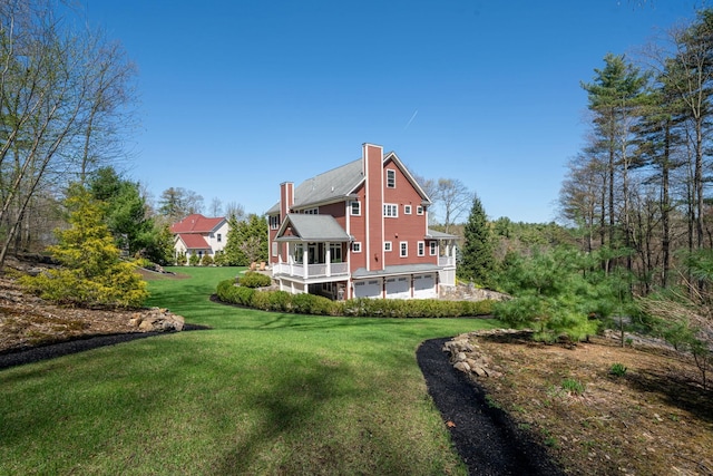 back of house with a garage, a chimney, and a lawn