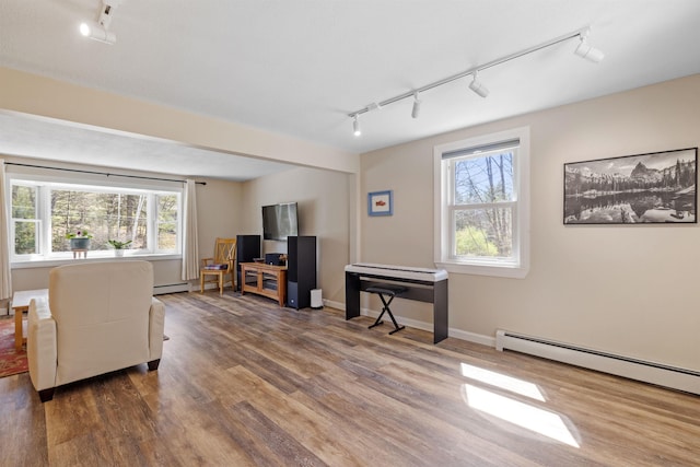 living room with a healthy amount of sunlight, track lighting, a baseboard radiator, and wood finished floors
