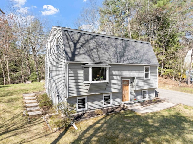 raised ranch with a shingled roof, a gambrel roof, a front lawn, and a chimney