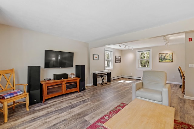 living room featuring baseboard heating, baseboards, track lighting, and wood finished floors