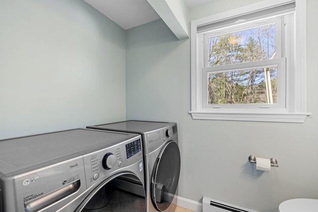 clothes washing area featuring separate washer and dryer, baseboards, a baseboard heating unit, and laundry area