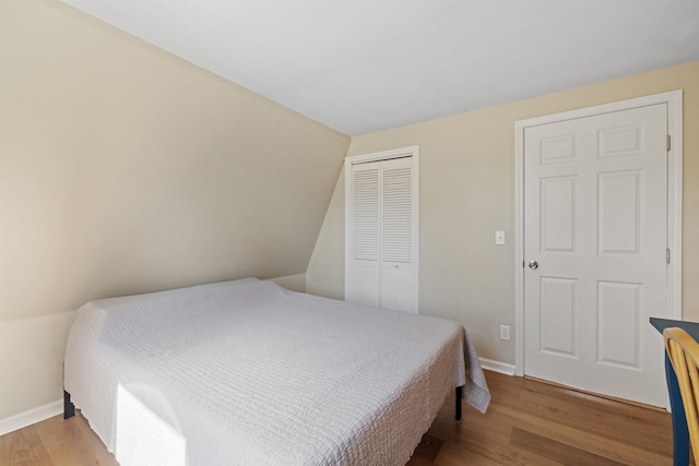 bedroom featuring baseboards, wood finished floors, and a closet