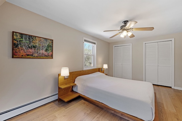 bedroom with ceiling fan, multiple closets, light wood-style flooring, and a baseboard radiator