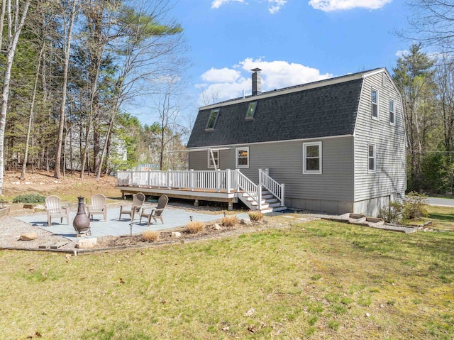 back of property with a lawn, a shingled roof, a patio area, and a deck