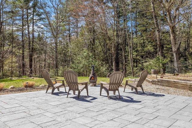 view of patio / terrace with an outdoor fire pit and a wooded view