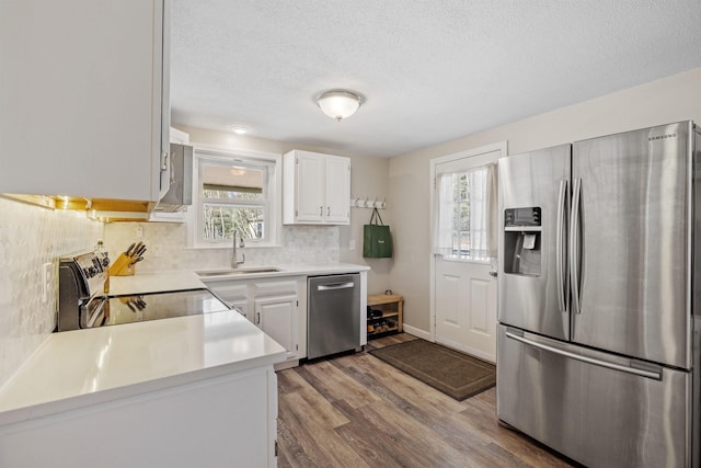 kitchen featuring appliances with stainless steel finishes, a sink, light countertops, a textured ceiling, and wood finished floors