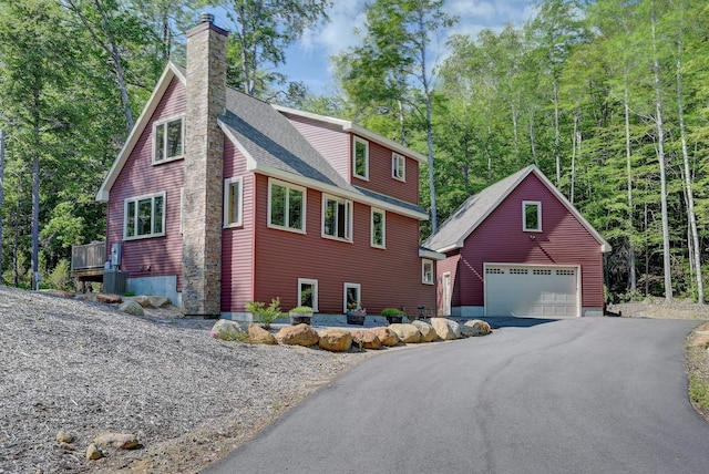 view of front of property with a shingled roof, an outbuilding, a chimney, and a detached garage