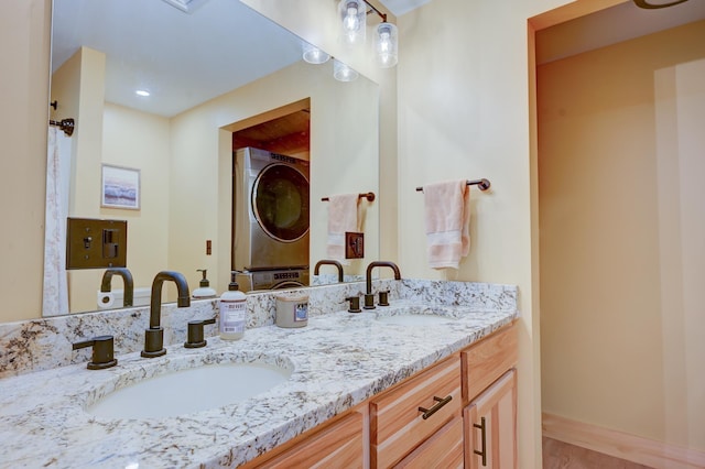 full bath featuring double vanity, a sink, stacked washer and clothes dryer, and wood finished floors