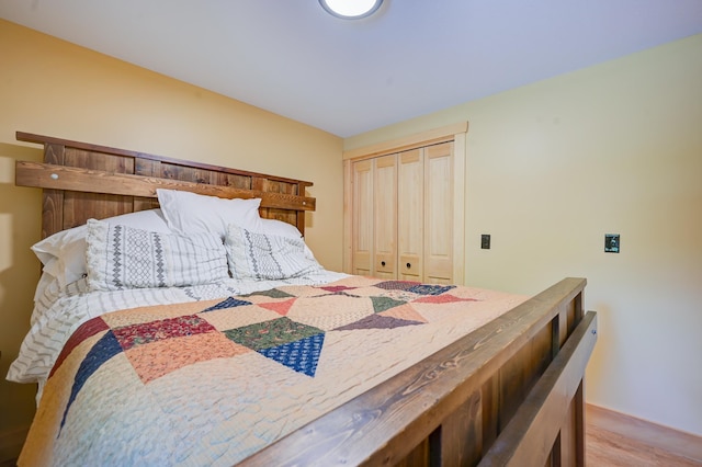 bedroom featuring light wood-style floors, baseboards, and a closet