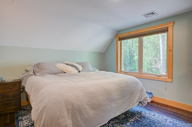 bedroom featuring baseboards, vaulted ceiling, wood finished floors, and visible vents