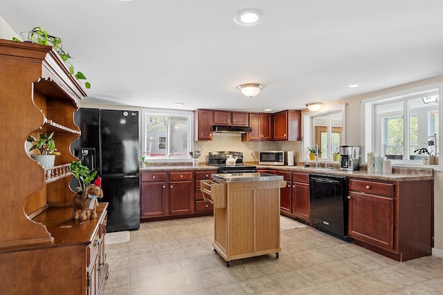 kitchen featuring under cabinet range hood, light floors, black appliances, and a center island