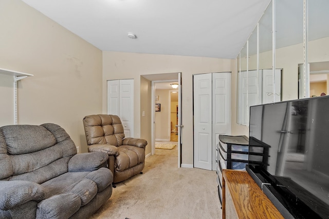 living area with baseboards, light colored carpet, and lofted ceiling