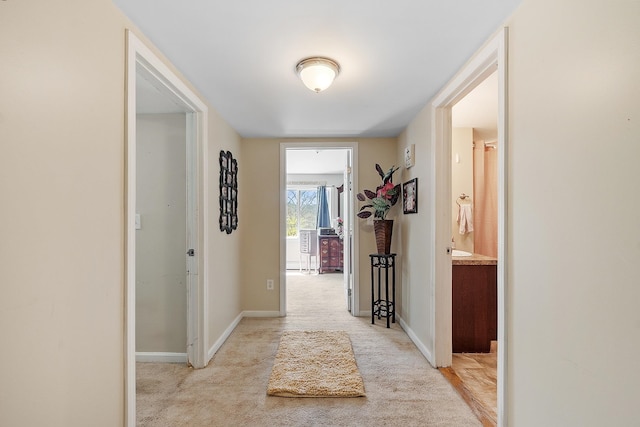 hallway with light colored carpet and baseboards
