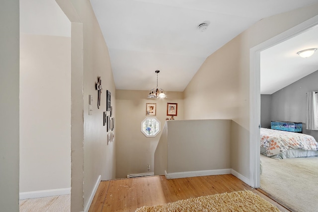 foyer entrance with baseboards, vaulted ceiling, wood finished floors, and a chandelier