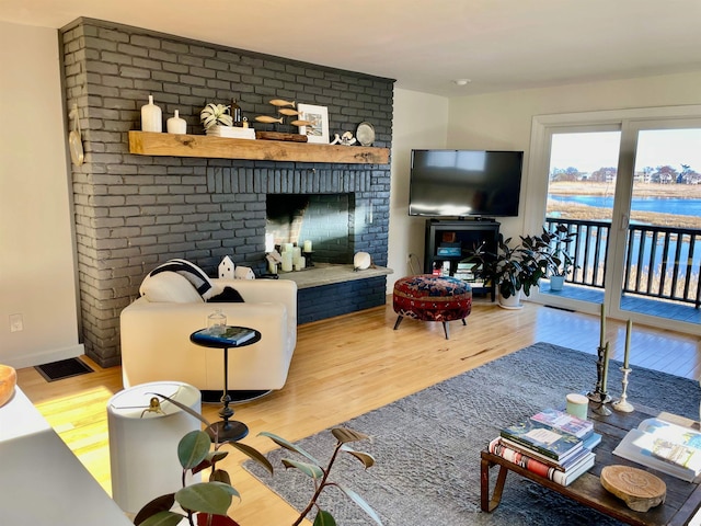 living area with a brick fireplace and wood finished floors
