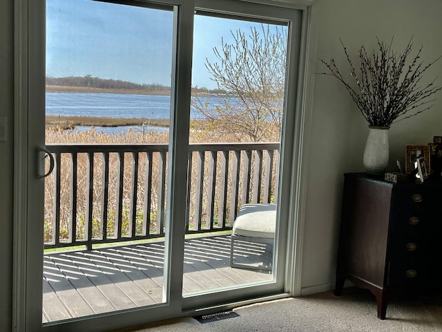 doorway to outside with carpet floors, a water view, and visible vents
