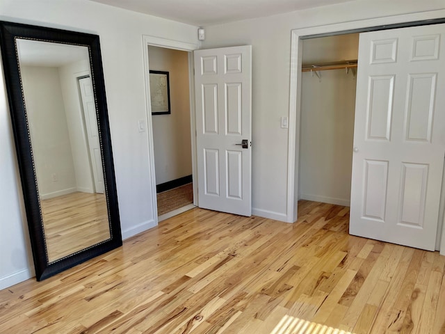 unfurnished bedroom featuring baseboards, light wood-style flooring, and a closet