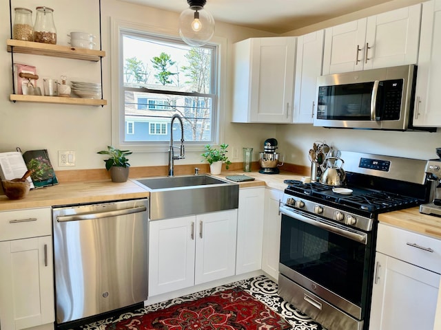 kitchen with white cabinetry, appliances with stainless steel finishes, wooden counters, and a sink