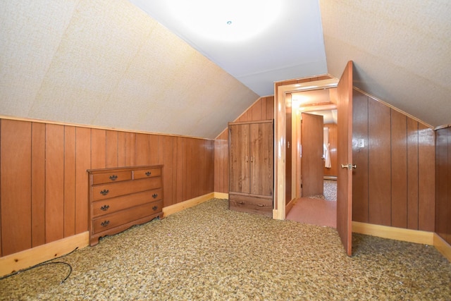 bonus room featuring wood walls, carpet, and vaulted ceiling