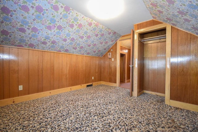 bonus room with wooden walls, elevator, wallpapered walls, vaulted ceiling, and visible vents