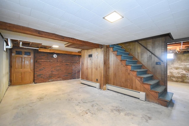 basement featuring wooden walls, a baseboard heating unit, and stairway