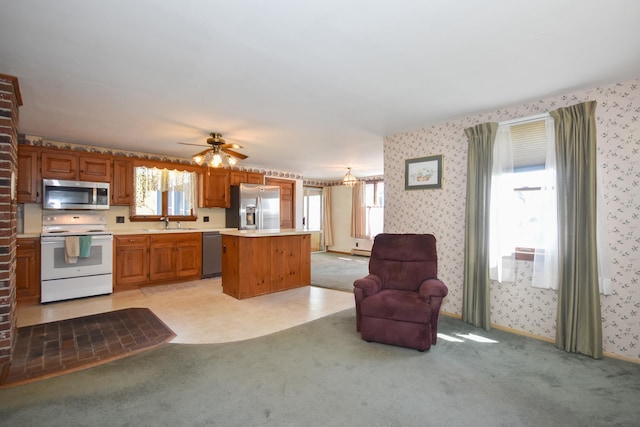 kitchen featuring light countertops, stainless steel appliances, open floor plan, and wallpapered walls