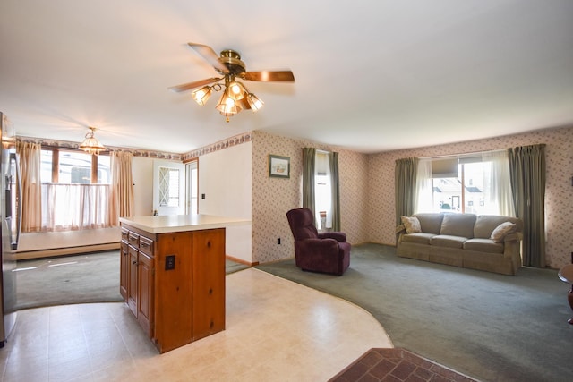 kitchen with ceiling fan, a center island, wallpapered walls, open floor plan, and a baseboard radiator