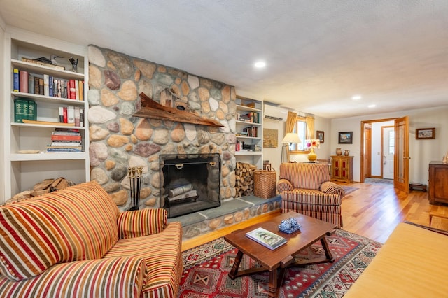 living room featuring a fireplace, a wall unit AC, recessed lighting, and wood finished floors