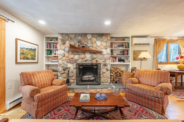 living area featuring a wall unit AC, a stone fireplace, built in shelves, wood finished floors, and a baseboard radiator