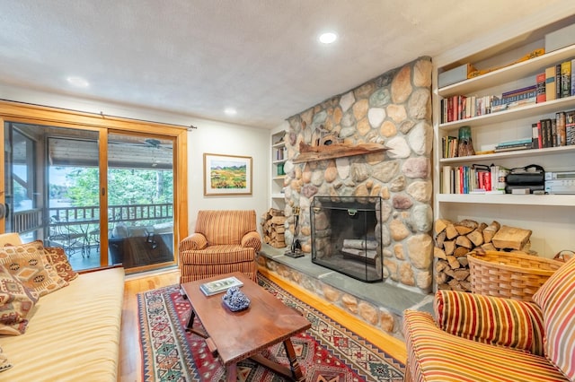 living area featuring a stone fireplace, recessed lighting, and wood finished floors