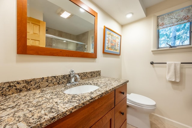 bathroom featuring vanity, tile patterned flooring, toilet, baseboards, and a shower stall