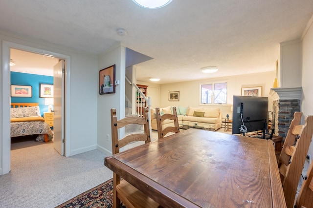 carpeted dining room featuring stairs, baseboards, and a stone fireplace