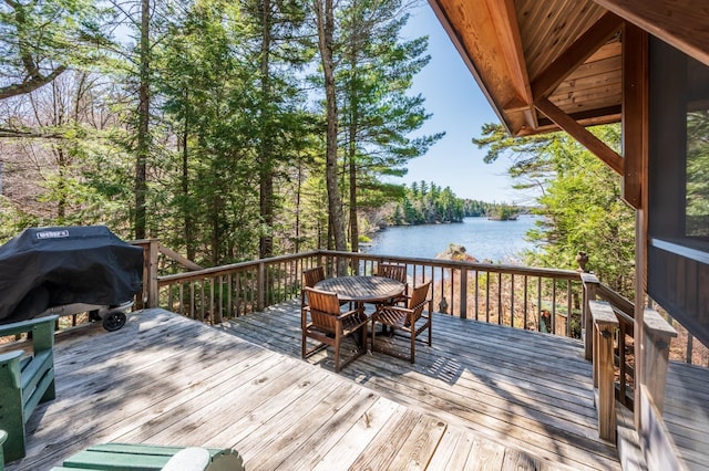 wooden terrace with a water view and outdoor dining area